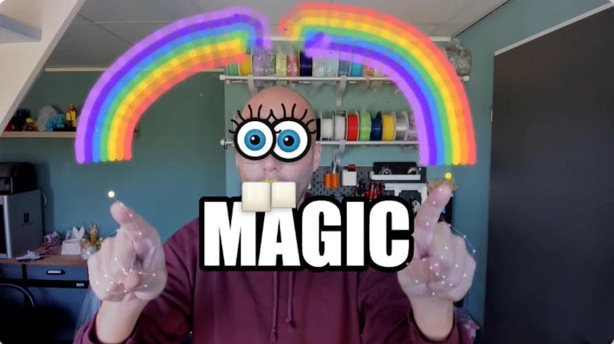 Man with both hands raised drawing rainbow arcs in the air using finger tracking, with cartoon Spongebob eyes overlaid on his face and MAGIC text on screen: MediaPipe hand and face detection demo